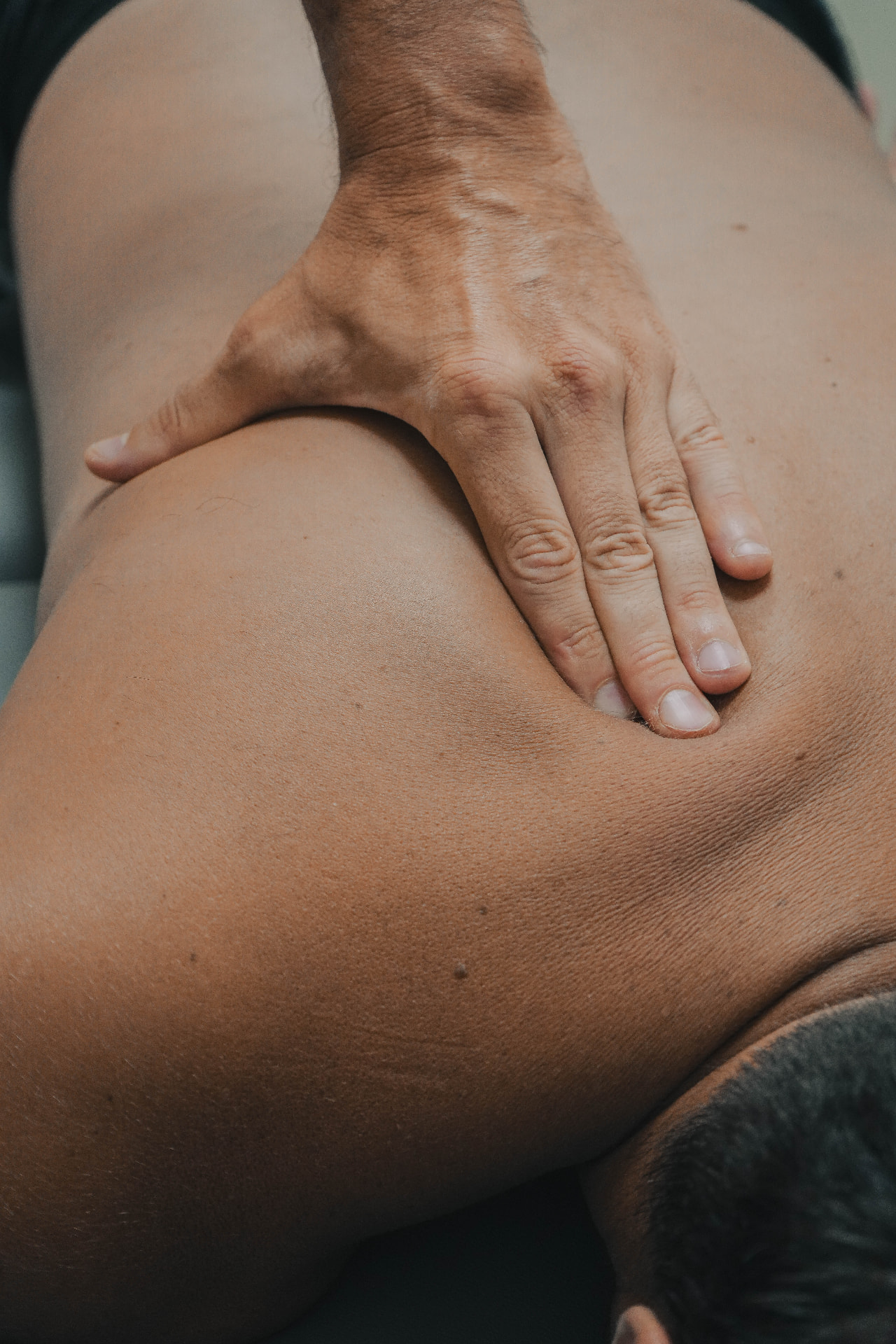 Mano de un fisioterapeuta aplicando presión sobre la espalda de un paciente